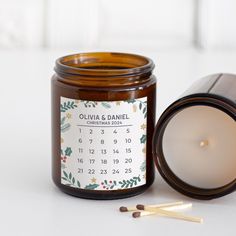 a candle and matches are next to a calendar on a glass jar that says oujava & danielle