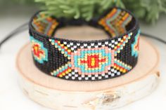 Introducing our southwestern cross cuff bracelet- perfect for adding a touch of boho chic to any outfit! This bracelet is handmade with black leather trim and colorful seed beads, and features an adjustable closure for a perfect fit. It is beaded on strong beading thread & flexible natural leather for comfortable stylish look. It can be worn alone or stacked with other pieces. 7/8 of an inch wide. This bracelet will fit a 6-8 inch wrist. When you purchase this bracelet, I make it to order, just Southwestern Black Beaded Bracelet With Colorful Beads, Southwestern Style Black Beaded Bracelet With Colorful Beads, Adjustable Black Cuff Bracelet With Colorful Beads, Handmade Southwestern Black Beaded Bracelets, Handmade Black Southwestern Beaded Bracelets, Black Beaded Southwestern Bracelets, Southwestern Black Beaded Bracelets, Southwestern Style Black Beaded Bracelets, Southwestern Black Bracelets For Festival