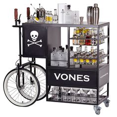 an old fashioned bar cart with bottles and glasses on the front, behind it is a bicycle