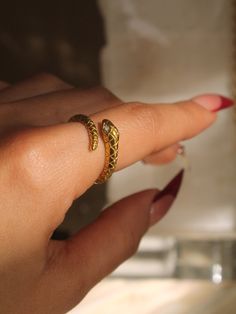 A snake, wrap-around ring with textured scale details and clear gemstones for eyes.. aka the SanZ Snake.  Materials: Gold PVD over Stainless Steel | Cubic Zirconia Water & sweat-resistant. Every purchase includes a gift box. Thank you for browsing the collection! :) Metal Snake Open Ring, Elegant Adjustable Metal Snake Ring, Adjustable Gold Metal Snake Ring, Elegant Metal Ring In Snake Shape, Elegant Snake-shaped Metal Rings, Elegant Snake Shaped Metal Rings, Adjustable Metal Snake Ring, Adjustable Tarnish-resistant Snake-shaped Jewelry, Adjustable Gold Snake Ring