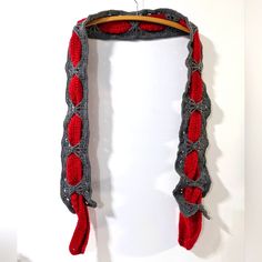 a red and gray scarf hanging on a white wall