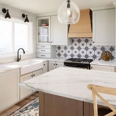 a kitchen with white cabinets and an island countertop in front of a stove top oven