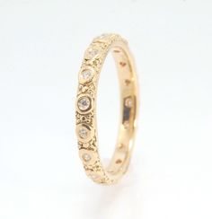 a yellow gold wedding ring with diamonds on the inside and outside, set against a plain white background