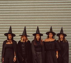 a group of women in witches costumes standing next to each other with their hands on their hipss