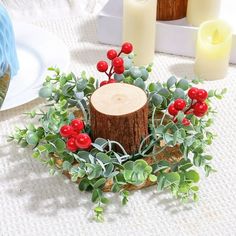 a table setting with candles and greenery in the center, along with a candle holder