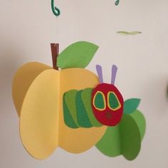 an apple and caterpillar mobile hanging from a wall