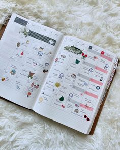 an open planner with stickers on it sitting on top of a white fluffy surface