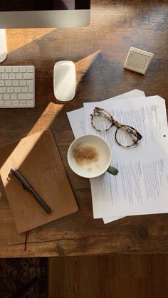 a cup of coffee sitting on top of a wooden desk