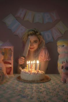 a woman holding a knife in front of a birthday cake