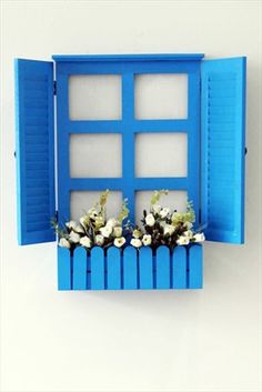 an open window with blue shutters and white flowers in the windowsill on a wall