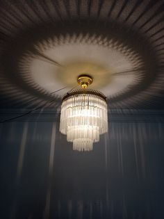 a chandelier hanging from the ceiling in a room with dark walls and shadows