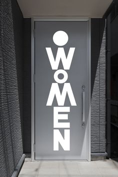 an open door with the word women on it in front of a black and white wall