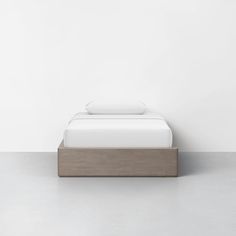 a bed sitting on top of a wooden platform next to a white wall and floor