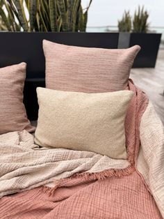 a bed with two pillows on top of it next to a potted palm tree