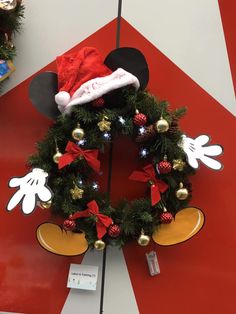 a mickey mouse wreath on display in a store with christmas decorations and lights around it