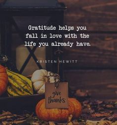 some pumpkins and gourds on the ground with a sign that says grateful helps you fall in love with the life you already have