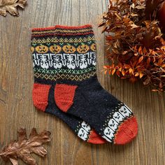 a pair of socks sitting on top of a wooden floor next to leaves and an autumn plant