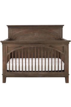 a wooden crib with white sheets on it