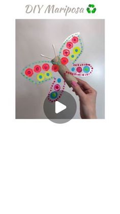 a hand holding a paper butterfly with buttons on it's wings and the words diy marposa