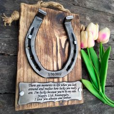 a wooden plaque with flowers and a pair of horseshoes on it next to some tulips