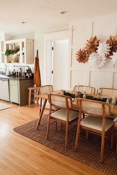 a dining room table and chairs in front of an open kitchen area with wood floors