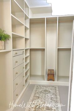 an empty walk in closet with white shelving and rug on the floor next to it