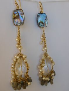 Large faceted Quartz Crystal drops, swing at the ends of 14KT gold fill Curb chain, intricately woven with tiny white Pearls  and glimmering silvery blue Labradorite ovals.. Shimmering Abalone at the top of the earrings, bring out the luster of these gems perfectly... Earwires and findings used in these earrings are 14KT gold fill   View more designs from Sirene del Mare...  www.sirenedelmare.etsy.com Pearl Cluster Earrings, Silvery Blue, Peacock Earrings, Pearl Cluster, Jewelry Making Tutorials, Blue Labradorite, Cluster Earrings, Crystal Drop, Rock Crystal