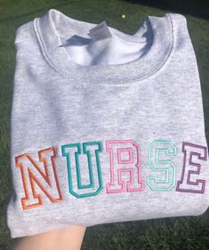 Personalized nurse sweatshirt with multi-colored embroidery! Small ash grey. Gray Letter Embroidery Sweatshirt For Fall, Gray Long Sleeve Sweatshirt With Letter Embroidery, Embroidered Gray Long Sleeve Sweatshirt, Gray Winter Sweatshirt With Embroidered Text, Gray Embroidered Winter Tops, Crew Neck Sweatshirt With Multicolor Embroidery, Multicolor Embroidered Text Crew Neck Sweatshirt, Gray Embroidered Text Sweatshirt For Fall, Gray Long Sleeve Top With Embroidered Text