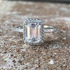 an emerald cut diamond ring with pave diamonds surrounding it