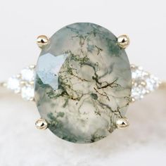 an oval shaped green and white stone surrounded by two diamond studded gold ring settings