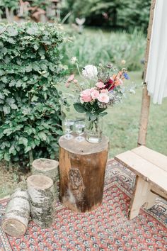 a vase filled with flowers sitting on top of a wooden table next to a bench