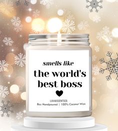 a candle that says smells like the world's best boss with snowflakes in the background