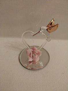 a pink rose sitting on top of a clear glass vase with a heart shaped handle