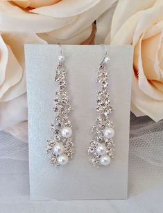 Romantic and elegant, this unique pair of earrings features iridescent white pearls and clear rhinestones that capture the light from every angle with a perfectly translucent appeal. The earrings are silver plated for a bright finish which enhances the intricate detailing and conveys a modern take on old elegance. French style ear wires with tiny pearl detail. Overall length of the earring is 2.5" (approx. 6.3cm) long and 0.6" (approx. 1.6cm) wide. This exquisite design will add a touch of sophi