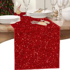 the table is set with plates, silverware and red sequined napkins