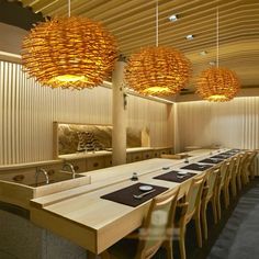 a long table with many place settings and lights hanging from it's ceiling in a restaurant