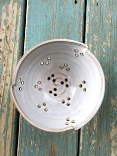 a white bowl sitting on top of a blue wooden table with holes in the bottom