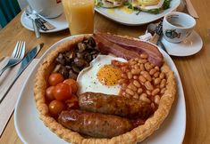 a breakfast plate with eggs, sausages, beans, tomatoes and bacon on it