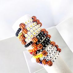 a stack of bracelets with words and basketball balls on them sitting on top of a white surface