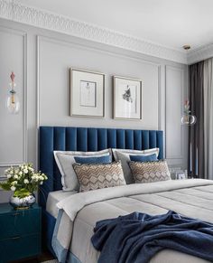 a large bed with blue headboard and pillows in a bedroom next to a window