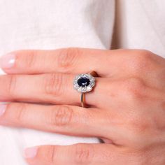 a woman's hand with a diamond and blue sapphire ring on her left hand