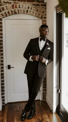 a man in a tuxedo standing next to a door