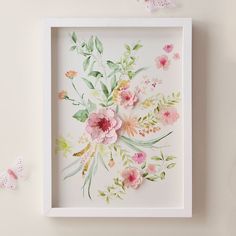 a white frame with pink and green flowers on it next to two butterfly shaped objects