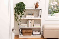 a bookshelf filled with lots of books next to a plant and a window