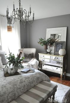 a bedroom with gray walls, white furniture and a chandelier hanging from the ceiling