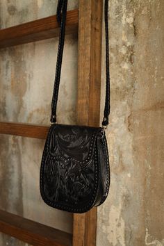 Unleash your inner fashionista with the Que Chula Chiquita Purse in stunning black! Crafted from top-quality tooled leather, this purse features a convenient front flap with a magnetic closure, as well as a detachable crossbody strap for versatile styling. Inside, you'll find a spacious interior pocket for all your essentials. Elevate any outfit with this must-have accessory! 8.5" (Height) x 3" (Depth) x 6.5" (Width) Beautiful tooled leather Scroll floral tooling on front and back of handbag Magnetic closure at top Cross-body style with adjustable leather strap Inner pocket Silver hardware Made in Mexico Black Hand Tooled Bags For Everyday Use, Black Hand Tooled Rectangular Shoulder Bag, Black Hand Tooled Shoulder Bag For Everyday, Black Leather Wallet With Adjustable Strap, Black Crossbody Saddle Bag With Magnetic Closure, Black Satchel Saddle Bag With Magnetic Closure, Combat Boots Heels, Felt Cowboy Hats, Straw Cowboy Hat