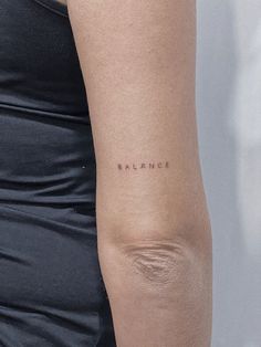 a woman's arm with the word balance tattooed on her left side ribcage