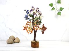 the small tree is made out of rocks and has colorful leaves on it's branches