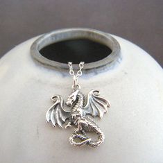 small sterling silver dragon necklace, 3/4" charm length - A solid sterling silver dragon, measuring 3/4" (21 mm) down and 7/8 inch across at widest point.   - Necklace chain is sterling silver cable chain, with lobster clasp and locking jump rings, all solid sterling silver. Length customizable at drop down menu. - Dragon has a lot of realistic detail on front, blackened (oxidized) to bring out those details. Back is smooth and slightly hollowed, with 925 mark. - Packaged in a modern circular t Silver Winged Fantasy Jewelry, Sterling Silver Fantasy Jewelry With Dragon Design, Fantasy Winged Jewelry Gift, Silver Fantasy Jewelry With Dragon Design, Fantasy Silver Jewelry With Dragon Design, Silver Fantasy Necklace Nickel Free, Fantasy Style Nickel-free Silver Necklaces, Nickel-free Fantasy Silver Necklace, Nickel-free Silver Fantasy Necklace