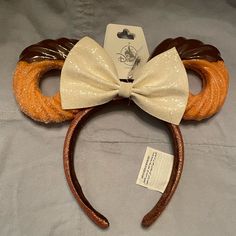 a mickey mouse ears headband with a white bow tie and brown leather ear clips